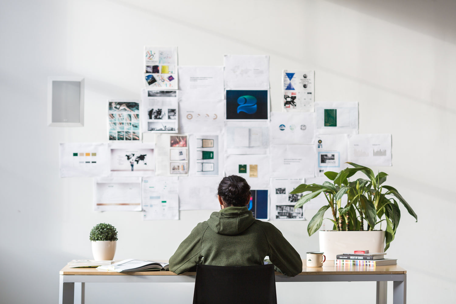 Student working at desk. Lot's of paper notes on wall.