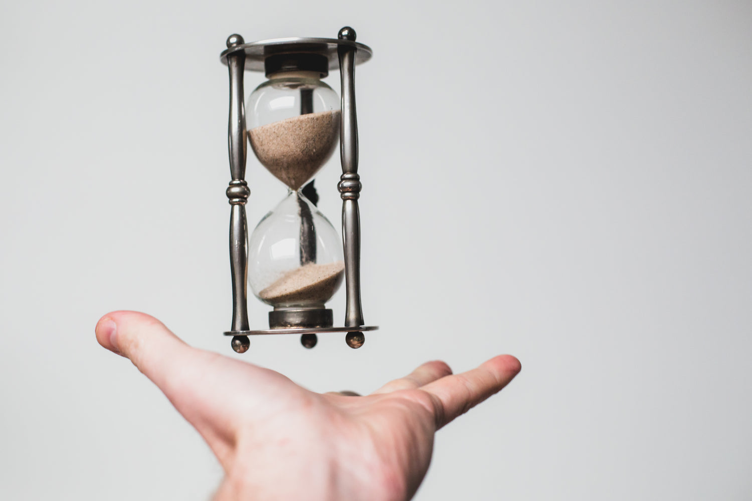 Hourglass hovering over man's hand.